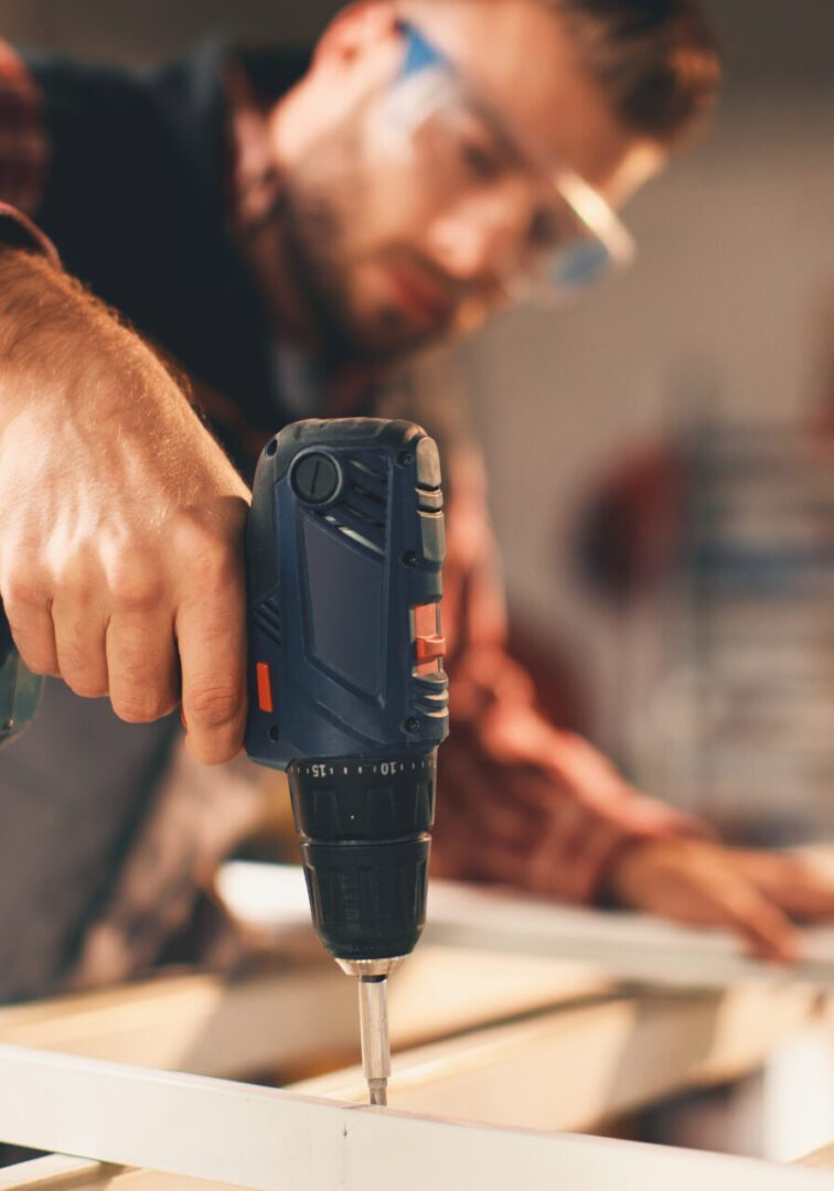 Young man working with drill in the workshop Man using a power drill on wood.