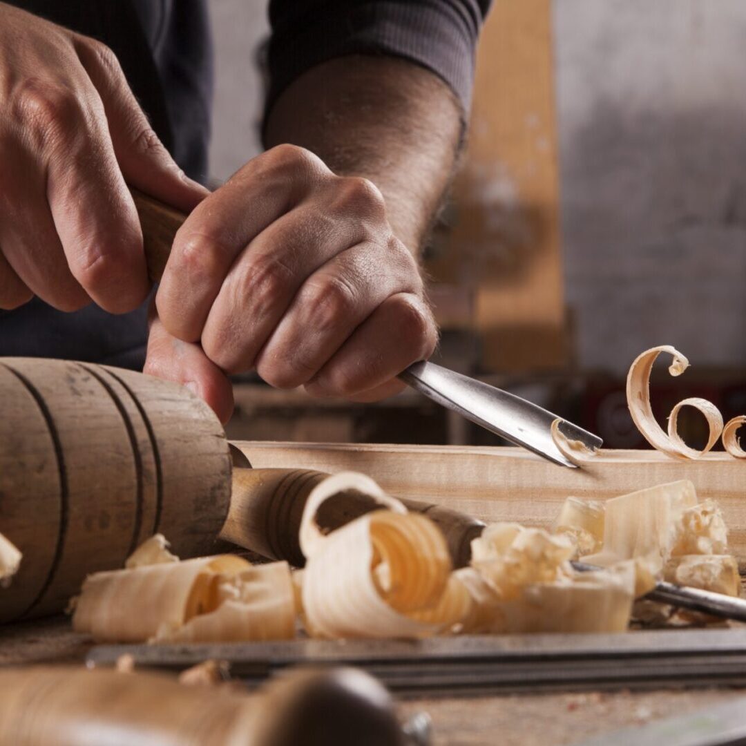 Hands of craftsman carve with a gouge Woodworker carving wood with chisel tools.